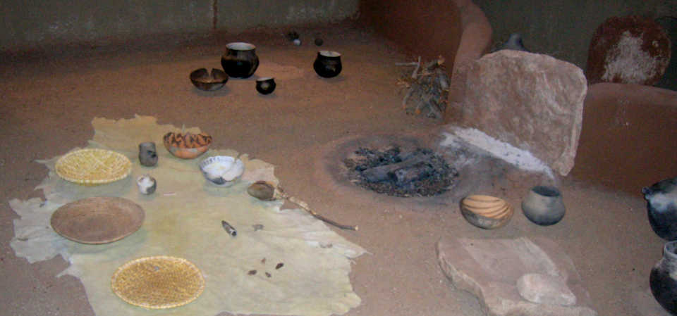 Various elements that were found in ancient pithouses on display: baskets, pottery, ladle, food grinding stones, fireplace, hearth