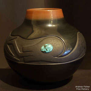Click for a larger version Lightly carved avanyu design with inlaid turquoise on a black jar with a sienna rim and partially slipped with micaceous clay